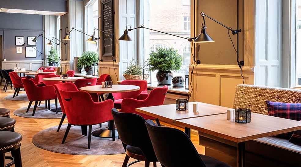 Sitteområde i restauranten med stoler og fine lamper ved vinduet ved Clarion Collection Hotel Temperance i Malmø