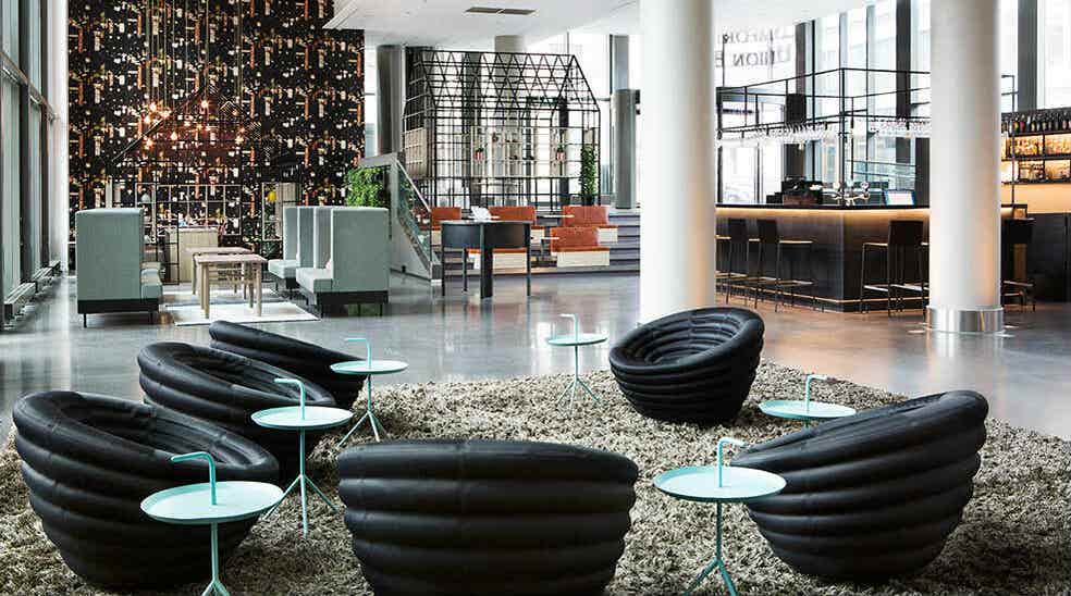 Lobby med interiørdetaljer, sorte stoler, bord og huskestativ ved Comfort Hotel Union Brygge Drammen