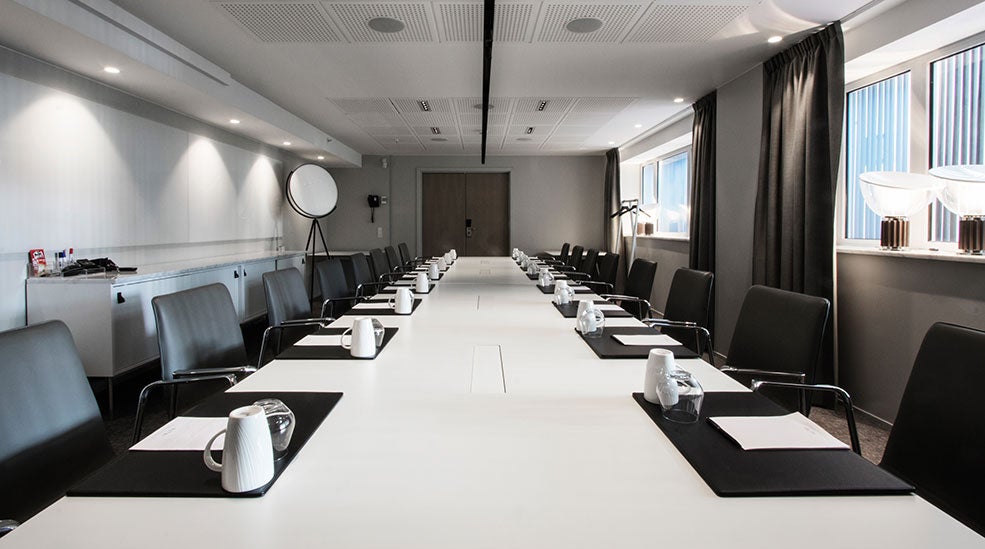 Meeting room with white table, black chairs, coffee cups at SKT. PETRI
