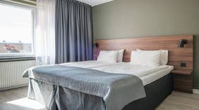 Sengeområde i Standard dobbeltrom med dobbeltseng, vindu og nattlampe på Quality Hotel Grand Kristianstad