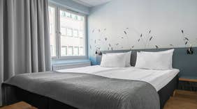 Moderne Standard dobbeltrom med Dobbeltseng, grått sengeteppe, grå gardiner og motiv på veggen ved Quality Hotel Grand Kristianstad 