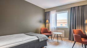 Standard Enkeltrom med seng, oransje stoler, vindu, lampe og bord på Quality Hotel Grand Kristianstad