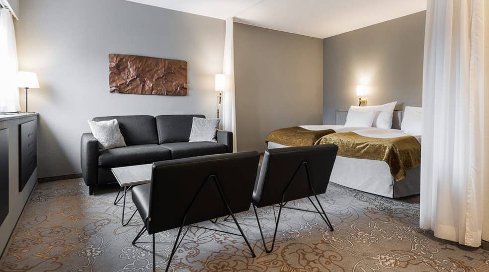 Grå sofa, dobbeltseng og svarte lenestoler i Deluxe dobbeltrom på Quality Hotel Royal Corner