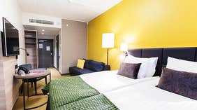 Superior dobbeltrom med dobbeltseng, sofa, gul vegg og sitteområde på Quality Hotel Winn Haninge